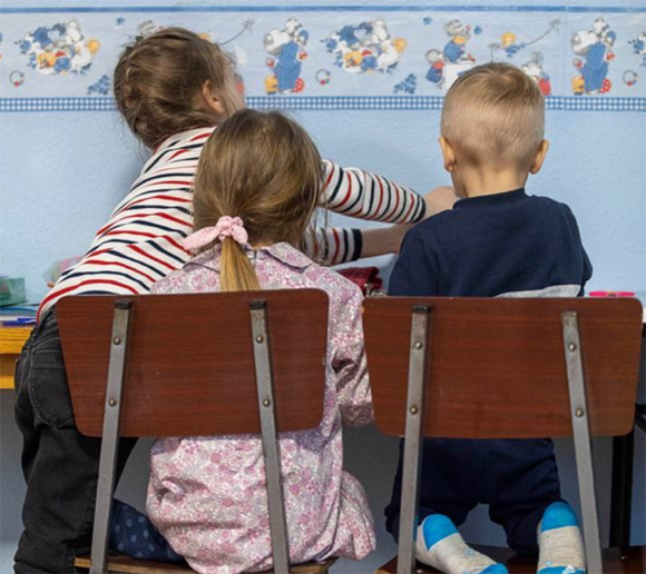 Imagen de tres niños de espaldas sentados en sillas | Foto de Fundación Banco Santander